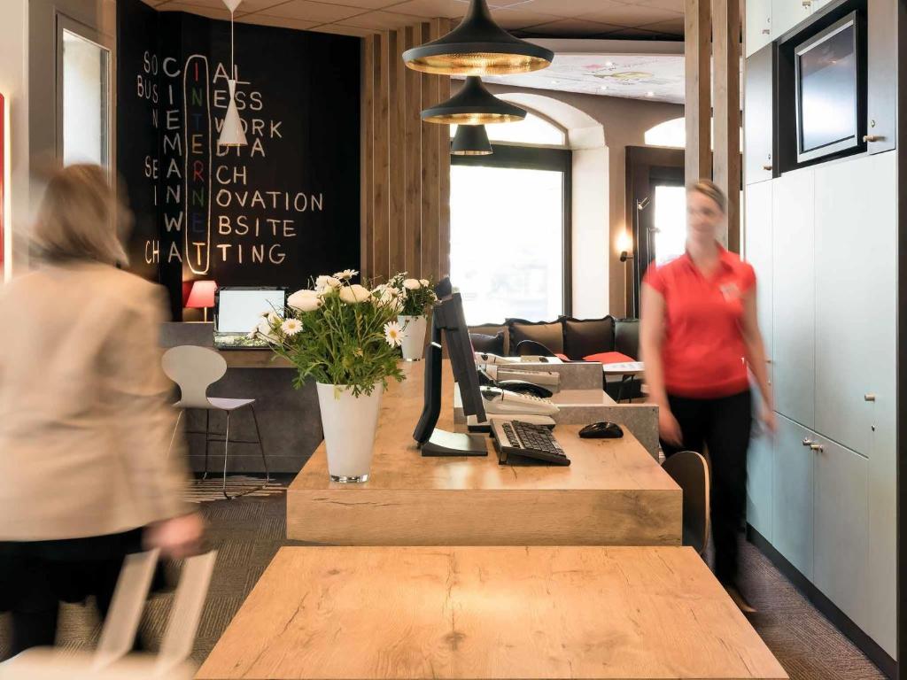 a woman is standing in an office with a table at ibis Angers Centre Chateau in Angers