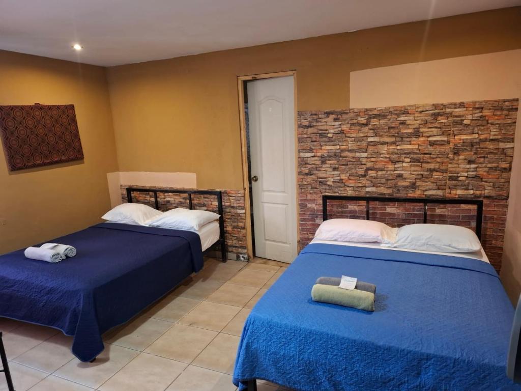 Alto BoqueteLegado Residence的一间卧室，有两张床和一堵砖墙