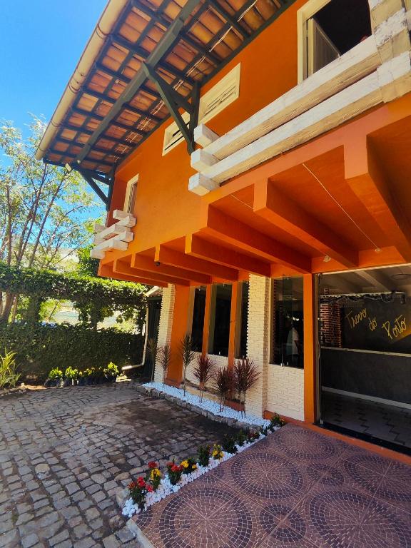 an orange building with a patio with flowers on it at Hotel Trevo do Porto in Porto Seguro
