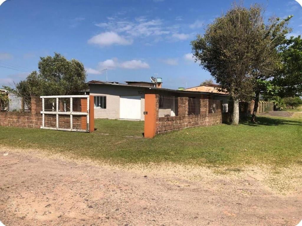 a brick house with an open door in a yard at Casa de praia - 2 quadras do mar in Arroio do Sal