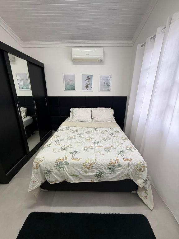 una camera da letto con un letto con un piumone e una finestra di Casa Bertioga Centro a Bertioga