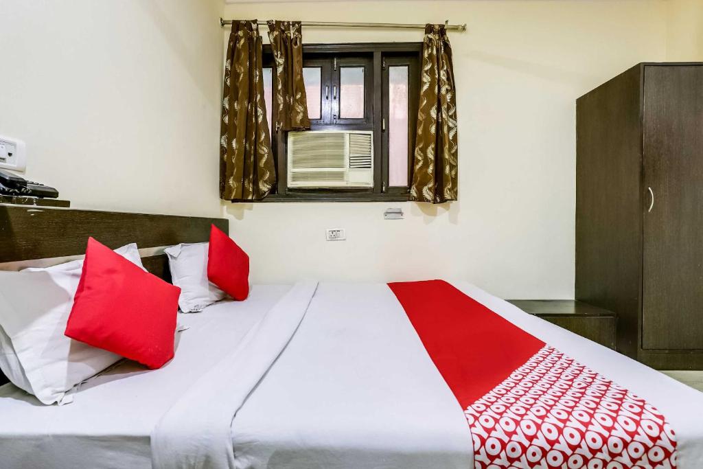 ein Schlafzimmer mit einem Bett mit roten und weißen Kissen in der Unterkunft Hotel O Grand Residency in Neu-Delhi
