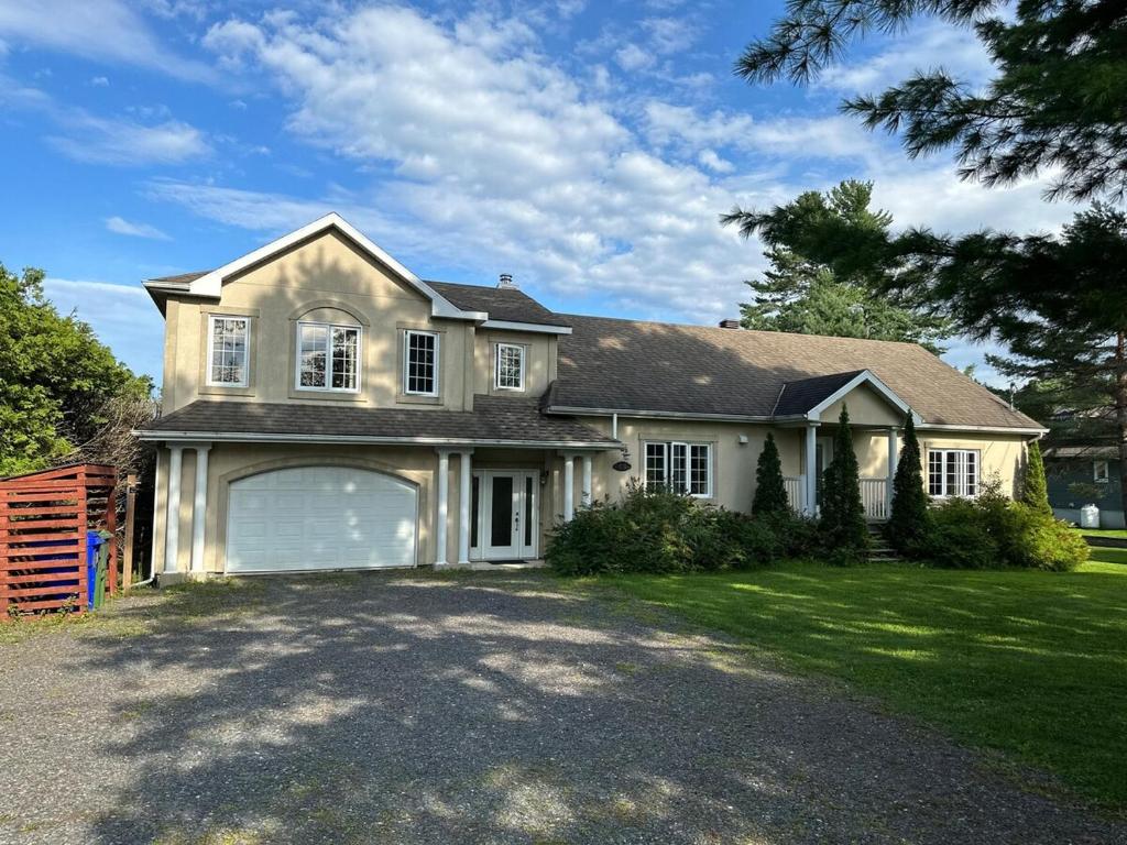 a large white house with a large garage at Havre du lac magog in Sainte-Catherine-de-Hatley