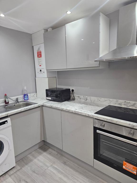 a kitchen with white cabinets and a sink and a stove at Penge lovely studio in Sydenham