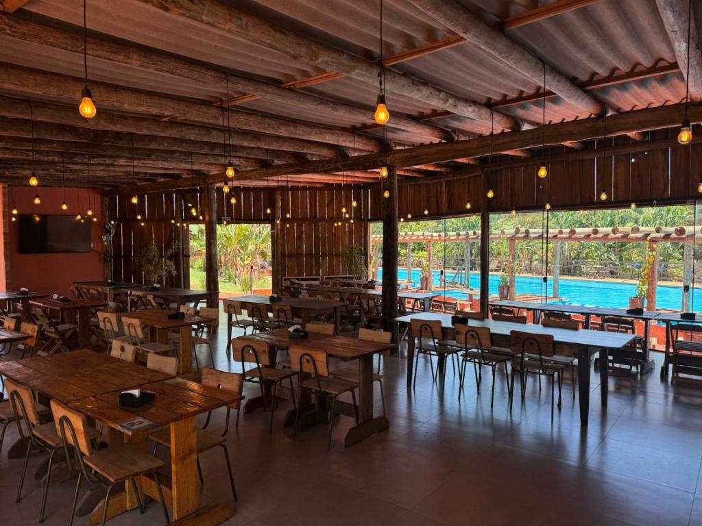 ein Restaurant mit Holztischen und -stühlen und Fenstern in der Unterkunft Fazenda Brotas SP in Brotas