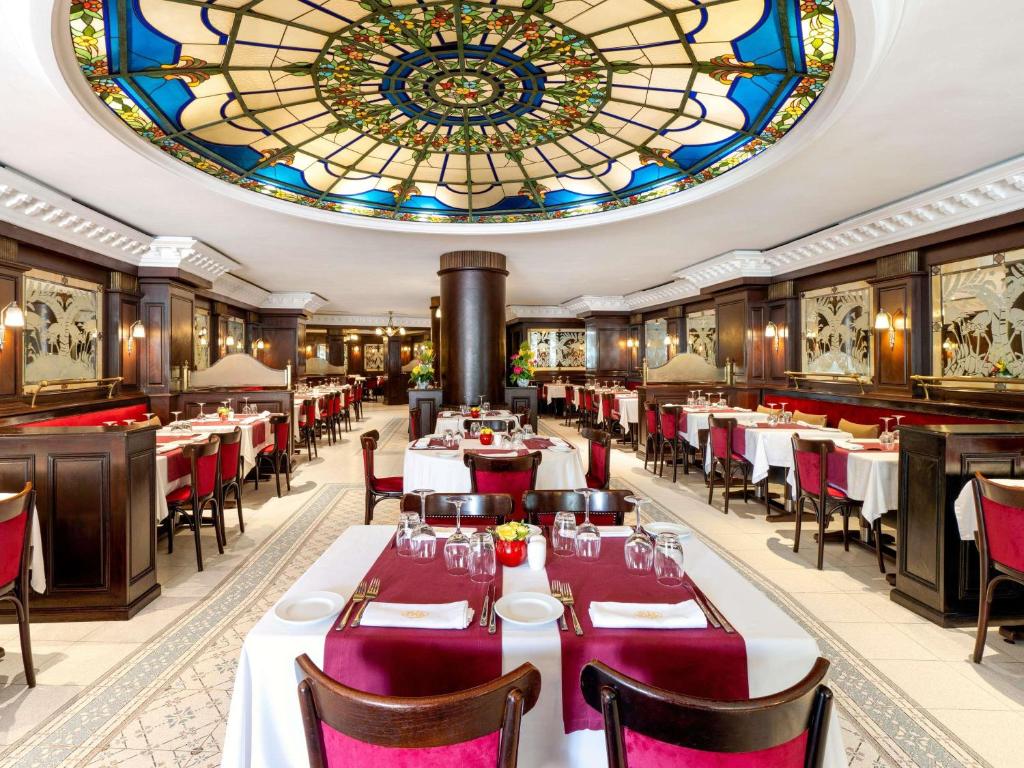 a restaurant with tables and chairs and a stained glass ceiling at Le Diwan Hotel Rabat - MGallery Collection in Rabat