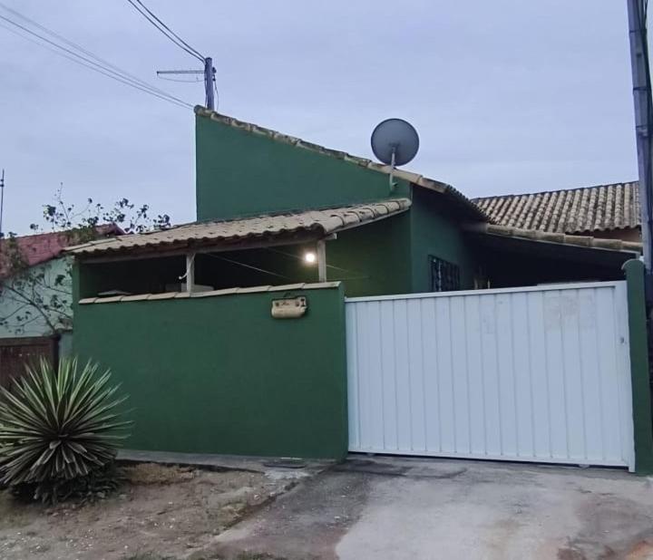 une maison verte et blanche avec une clôture blanche dans l'établissement Casa de praia Região dos Lagos - CASA VERDE - Unamar - Cabo Frio RJ, à Cabo Frio