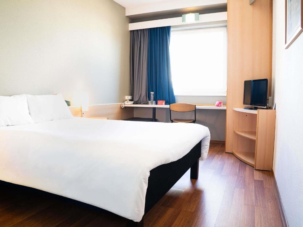 ein Hotelzimmer mit einem großen weißen Bett und einem Fenster in der Unterkunft Hotel Ibis Łódź Centrum in Łódź