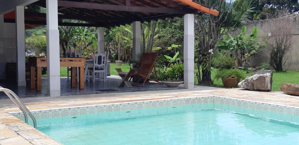 a swimming pool with a table and a pavilion at Ponta Negra Hospedagem in Maricá