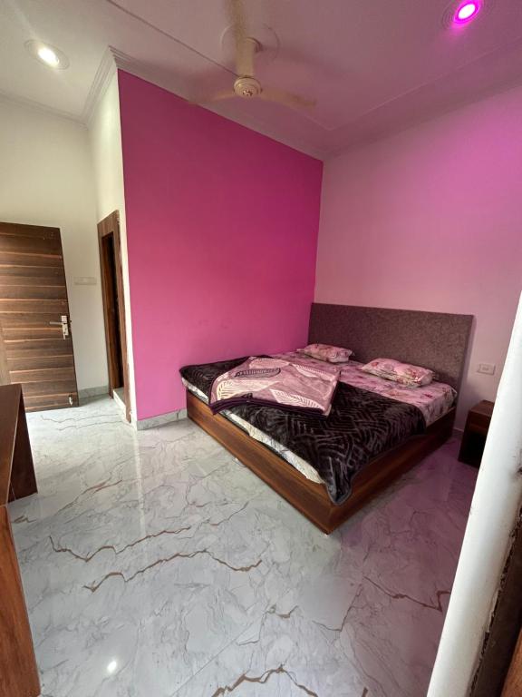 ein Schlafzimmer mit einer rosa Wand und einem Bett in der Unterkunft Hello India home stay in Khajurāho