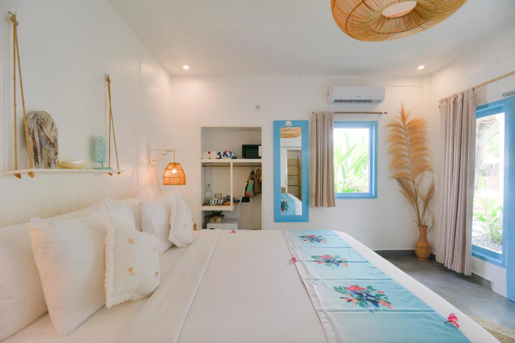 una camera da letto con un grande letto bianco con cuscini bianchi di The Koho Air Hotel a Gili Air