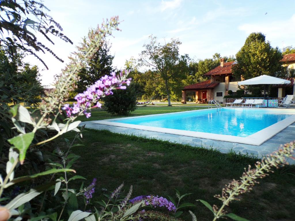 una piscina en el patio de una casa con flores púrpuras en Ca'Rino, en Bene Vagienna