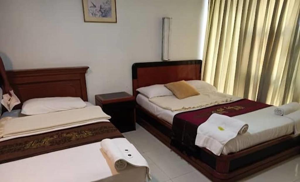 um quarto com duas camas e uma janela com cortinas em J Hotel Bukit Bintang em Kuala Lumpur