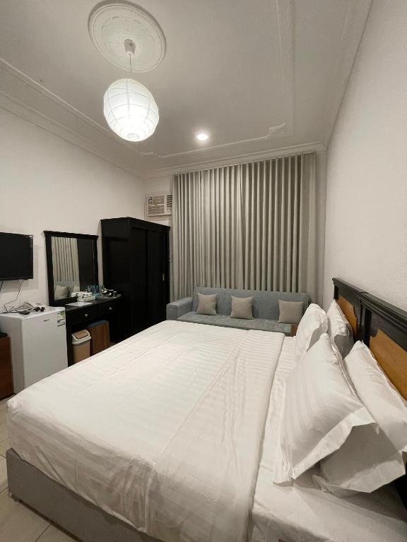 een slaapkamer met een groot wit bed en een bank bij كيان الين البديع in Abha