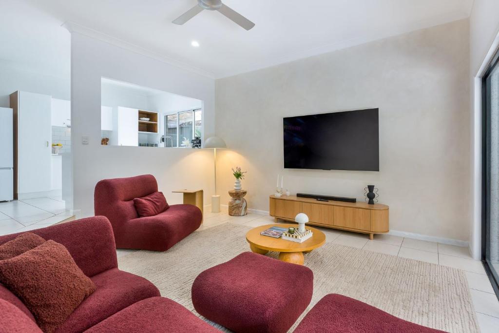 ein Wohnzimmer mit roten Stühlen und einem Flachbild-TV in der Unterkunft Stylish Family Retreat in Varsity by Housemark Escapes in Gold Coast