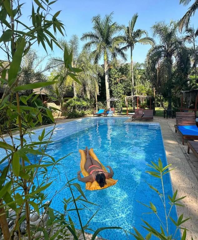 a man laying on a paddle board in a swimming pool at Cabañas Parana Ranch in Ituzaingó