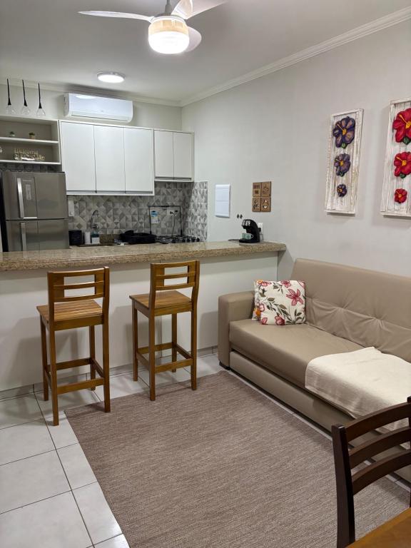 een woonkamer met een bank en een keuken bij Riviera Flat 120 - Com serviços de hotelaria in Riviera de São Lourenço