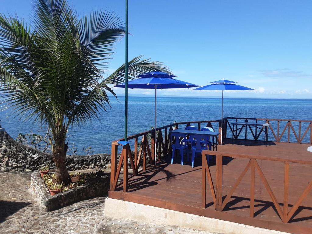 un ponte di legno con tavoli blu e ombrelloni sulla spiaggia di Sunset Vista Sea Front Guest House a Camotes Islands