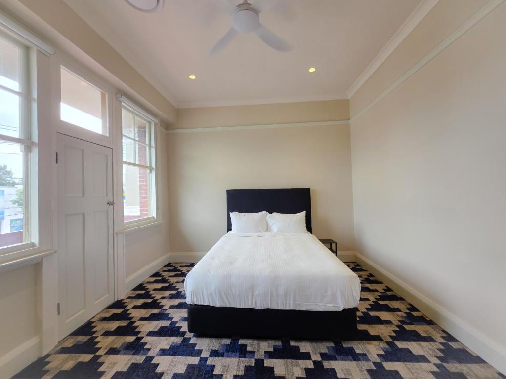 シドニーにあるRiverview Hotel Tempeのベッドルーム1室(白いシーツと天井付)