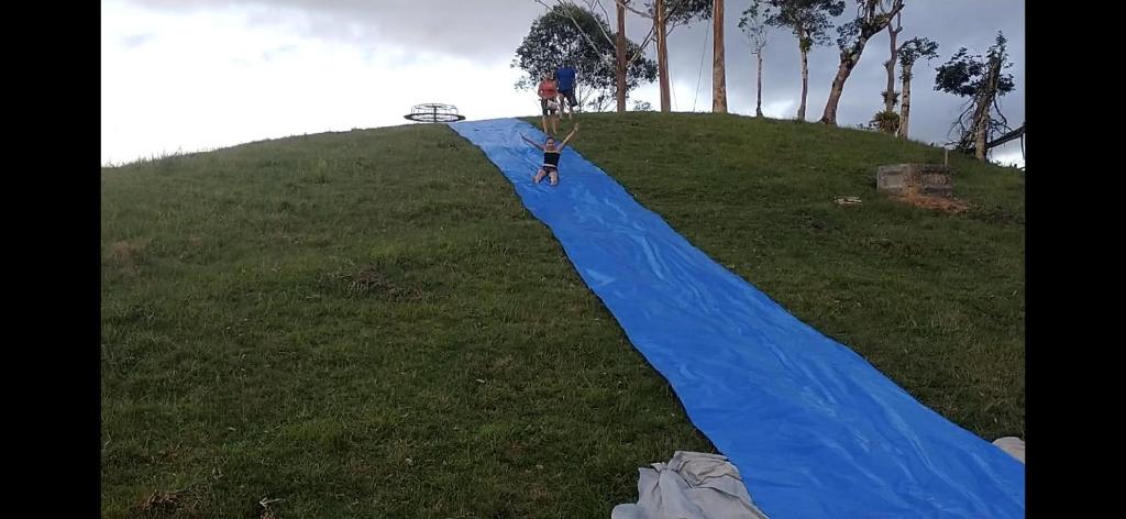 eine blaue Plane auf einem grasbewachsenen Hügel in der Unterkunft Chalés Refúgio nas montanhas in Guaratuba
