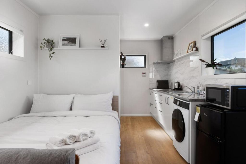 une petite chambre blanche avec un lit et un lavabo dans l'établissement Studio Unit 5 Mins Walk to CBD, à Gisborne