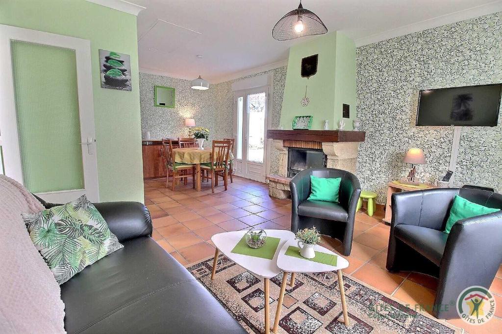 a living room with a couch and chairs and a fireplace at Le jardin in Plestin-les-Grèves