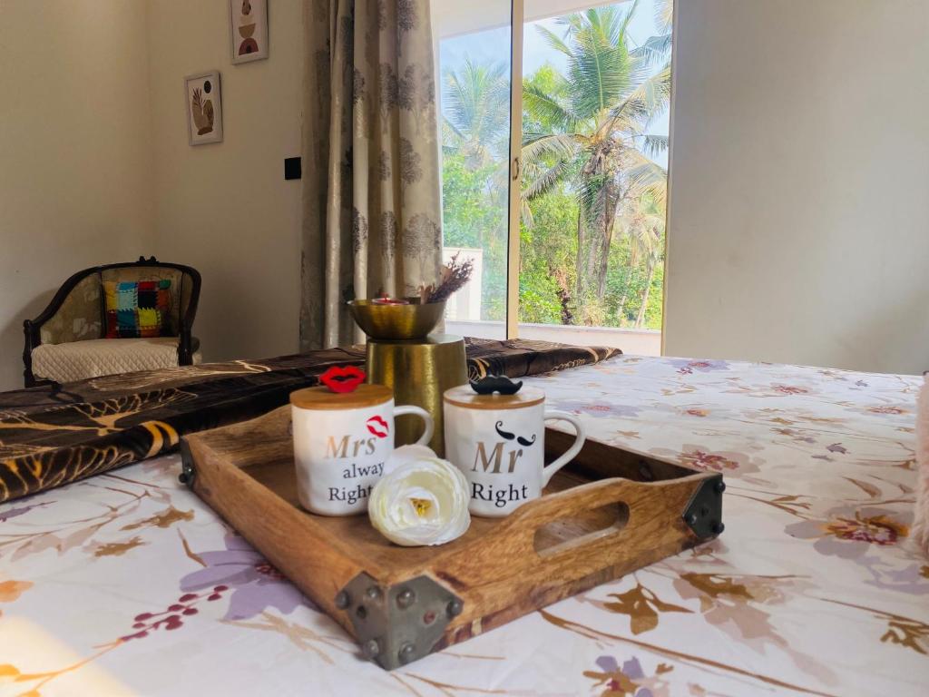 uma bandeja com duas xícaras numa cama em Casa Nauka em Colva
