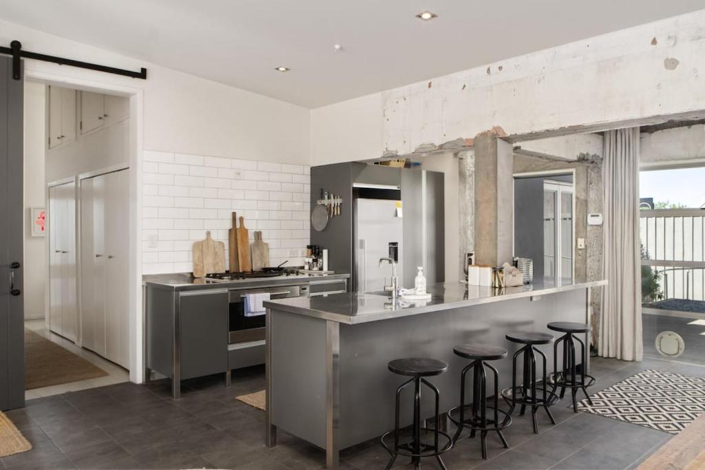 une cuisine avec un comptoir et un bar avec tabourets dans l'établissement Renovated 3BR Apartment in CBD, à Gisborne