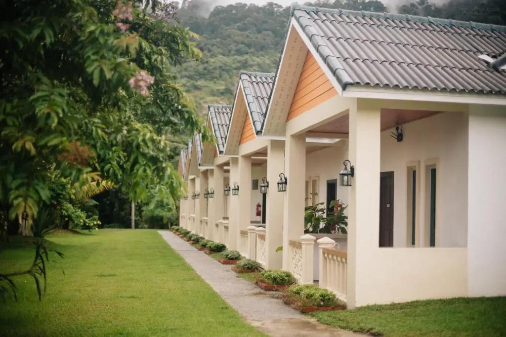 une rangée de bâtiments blancs avec une cour gazonnée dans l'établissement TC Garden Resort, à Kuah
