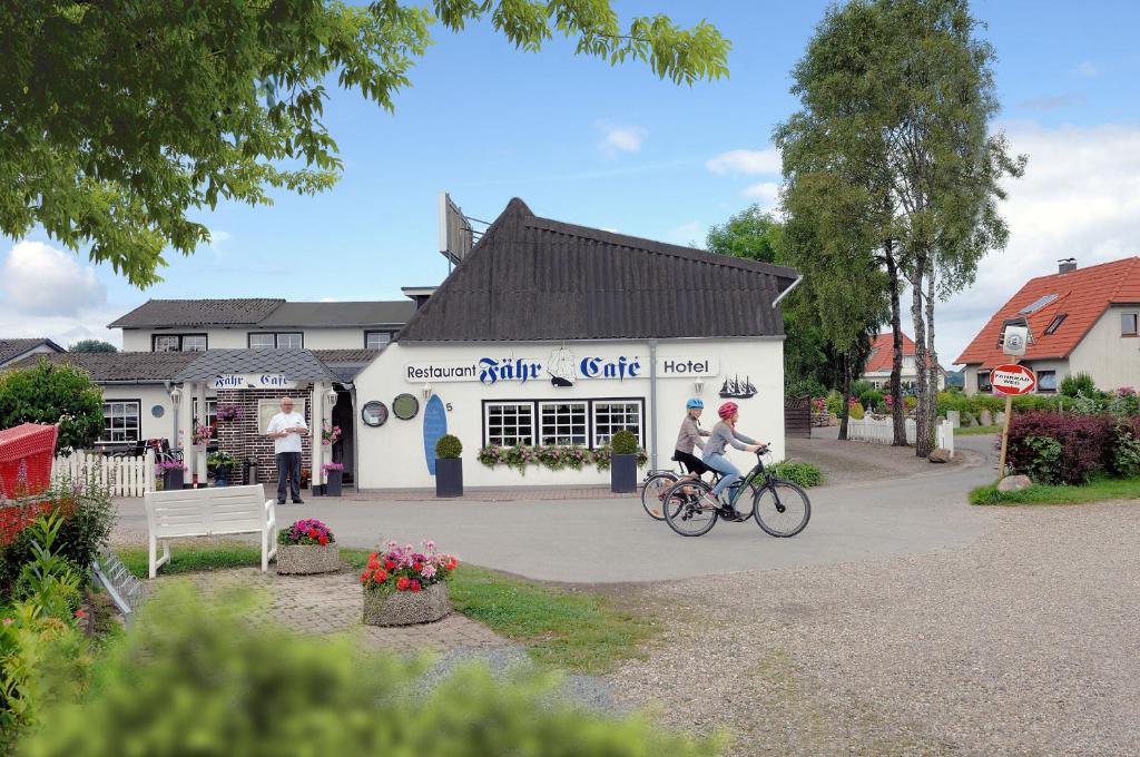 two people riding a bike in front of a building at Hotel-Restaurant Faehr-Cafe in Niesgrau