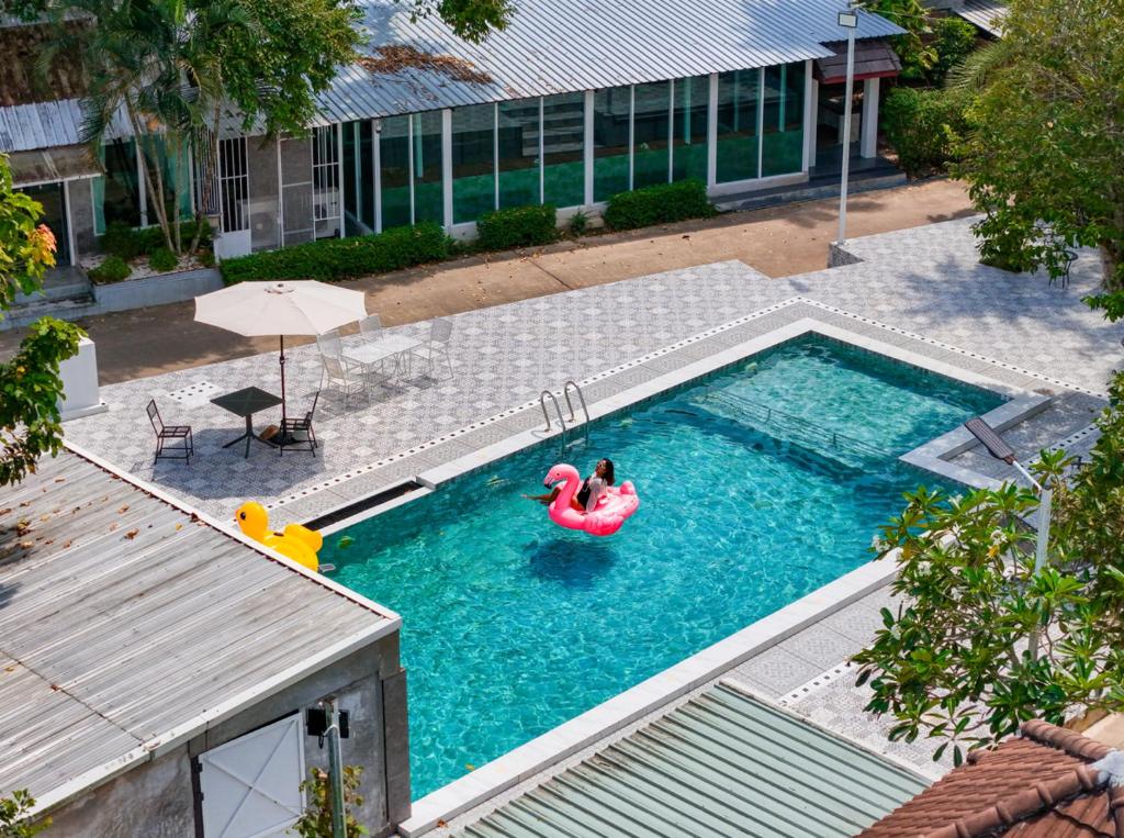 a person in a pool with a flamingo in the water at Kenikar Raintree Resort Chumphon in Chumphon