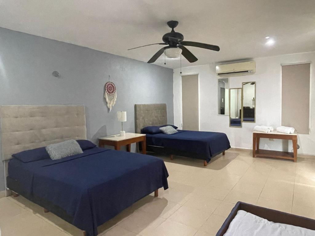 Un dormitorio con dos camas y un ventilador de techo. en Departamento AAK, en Mérida