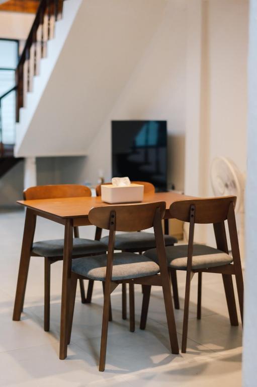 a wooden table with two chairs and a table with a television at Peaceful 2BR Home Walk to Halal Street Food in Hat Yai