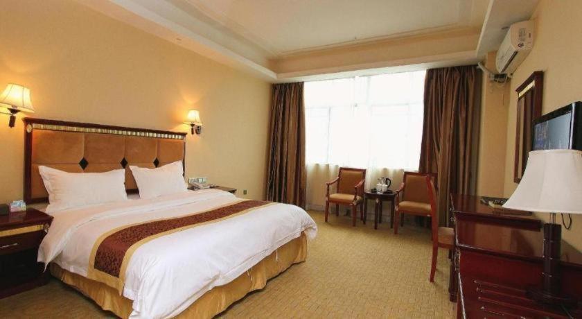 ein Hotelzimmer mit einem Bett und einem großen Fenster in der Unterkunft Shengshi Jinhua Hotel in Longgang