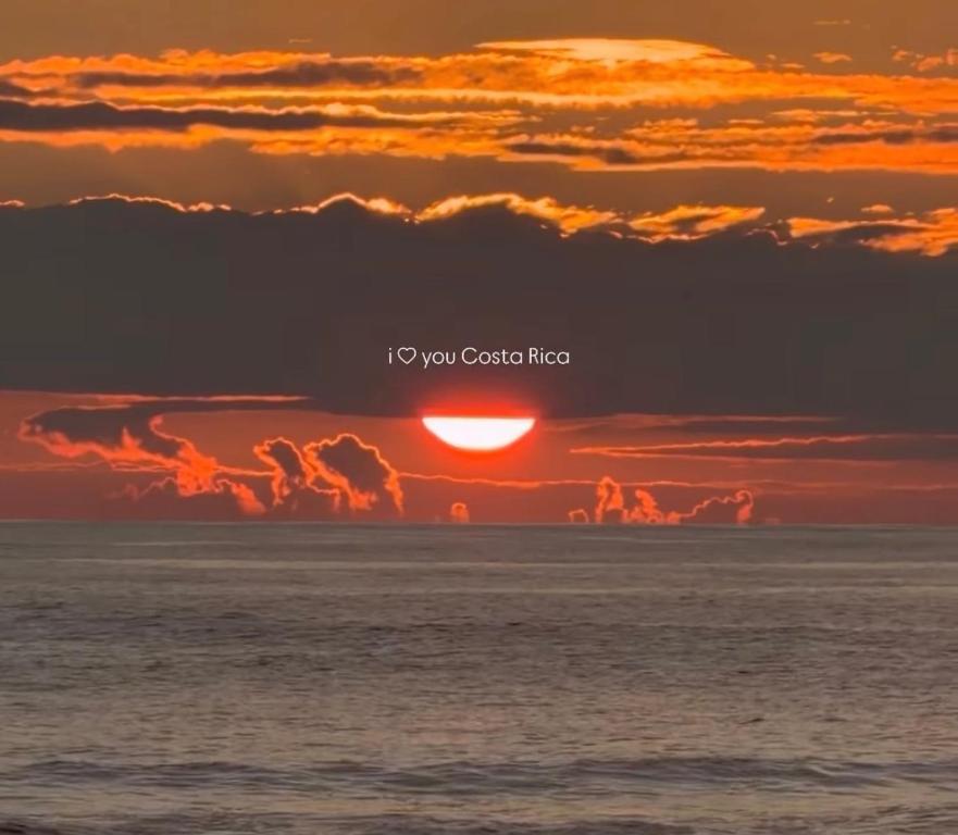 Surf VIP location في Cóbano: غروب الشمس فوق المحيط مع الكلمات "أنا أنت" و"النار"