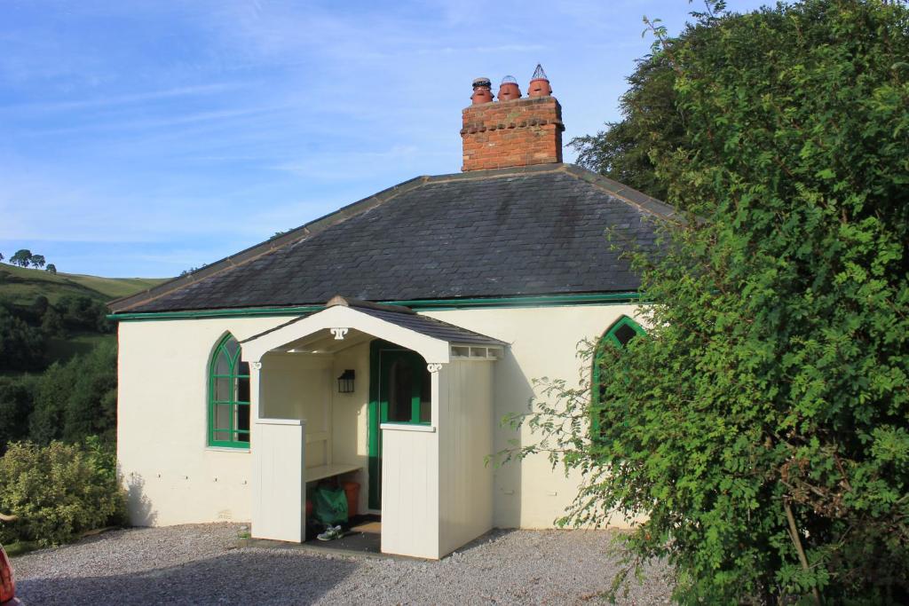 a small white building with a black roof at Glyn Arthur Lodge in Llandyrnog