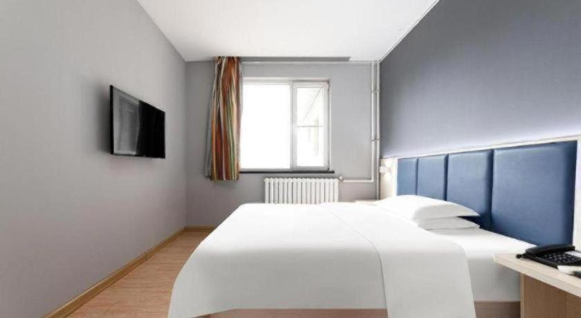 ein Schlafzimmer mit einem großen weißen Bett und einem Fenster in der Unterkunft 7 Days Inn Tianjin South Railway Station in Tianjin