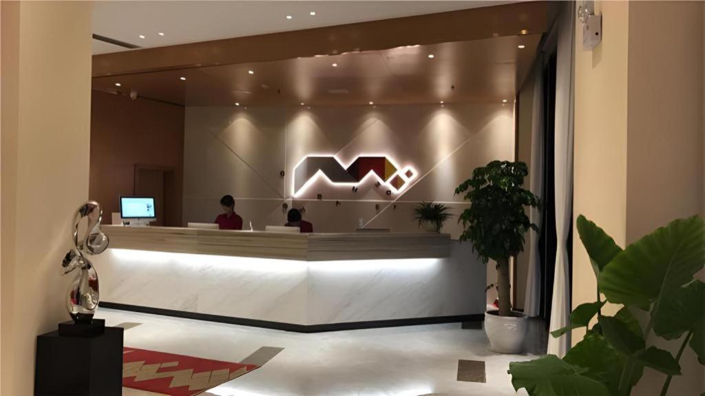 a lobby with a reception desk with a m logo at Borrman Hotel Jingzhou Jiangjin West Road Wanda Plaza Fantawild in Caoshi