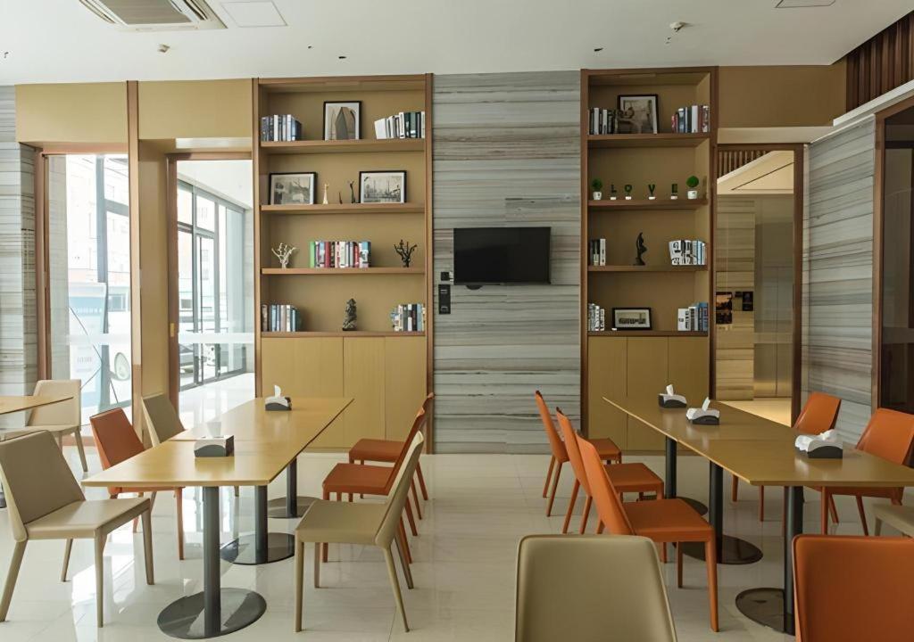 a restaurant with tables and chairs and a tv at City Comfort Inn Guigang Hecheng Wanda Plaza in Guigang