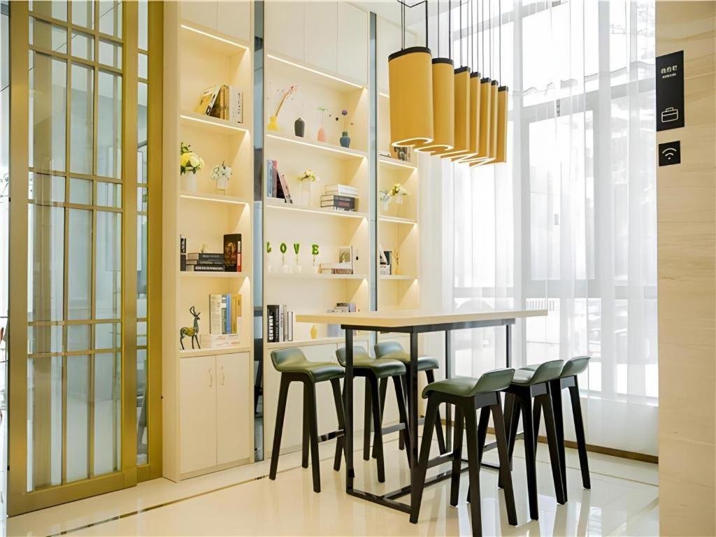 a dining room with a table and stools at City Comfort Inn Wanning Wan'An Avenue High Speed Railway Station in Wanning