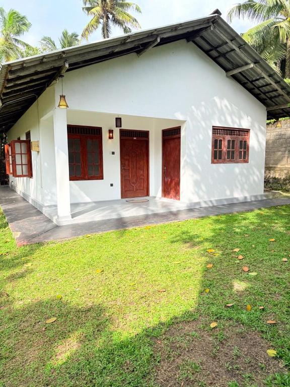 una casa blanca con puertas rojas y un patio en Dushan's House, en Ahangama