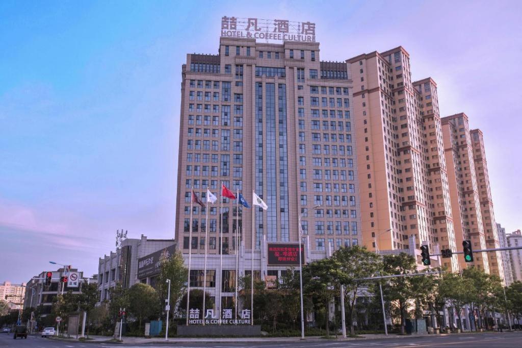 ein hohes Gebäude mit chinesischen Flaggen davor in der Unterkunft James Joyce Coffetel· Changde Liuyehu in Changde