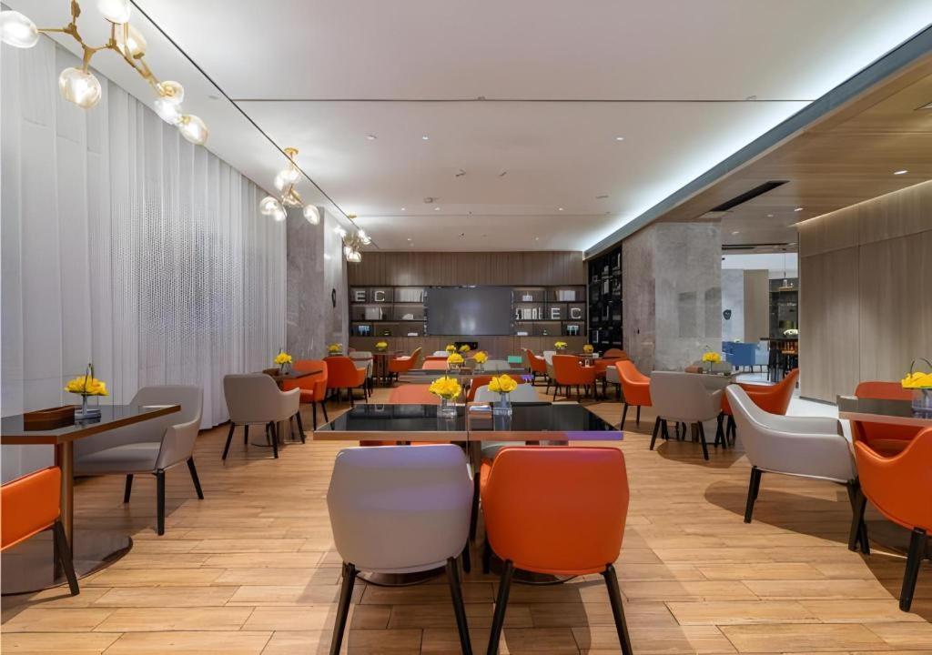 un restaurant avec des tables et des chaises orange et blanches dans l'établissement Echarm Hotel Tai'an Taishan Tianwai Village Hongmen, à Tai'an