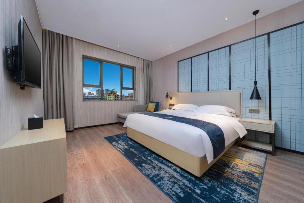 a bedroom with a large bed and a television at Echarm Hotel Nanchang Bayi Square Metro Station Wushang MALL in Nanchang