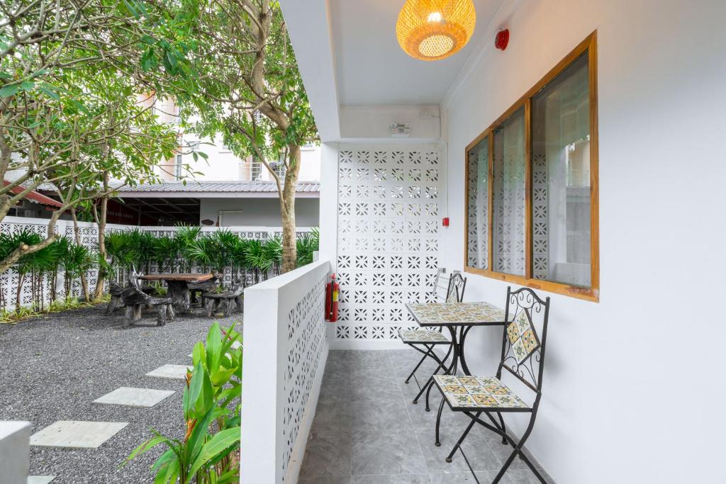 a patio with chairs and tables and trees at The Banyan House in Patong Beach