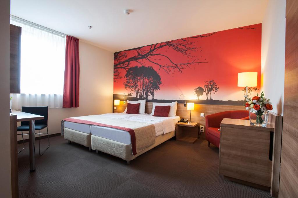 um quarto de hotel com uma cama e uma parede vermelha em Expo Congress Hotel em Budapeste