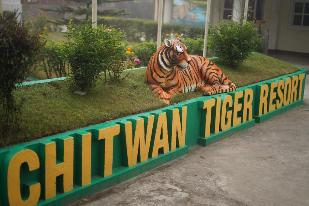 une statue de tigre assis sur l'herbe dans l'établissement Sishwar Chitwan Tiger Resort, à Meghauli