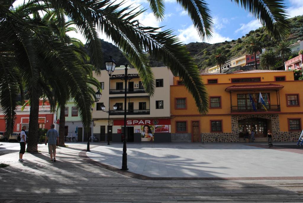 a street with palm trees in front of a building at Hostal Casa Amaya in Vallehermoso