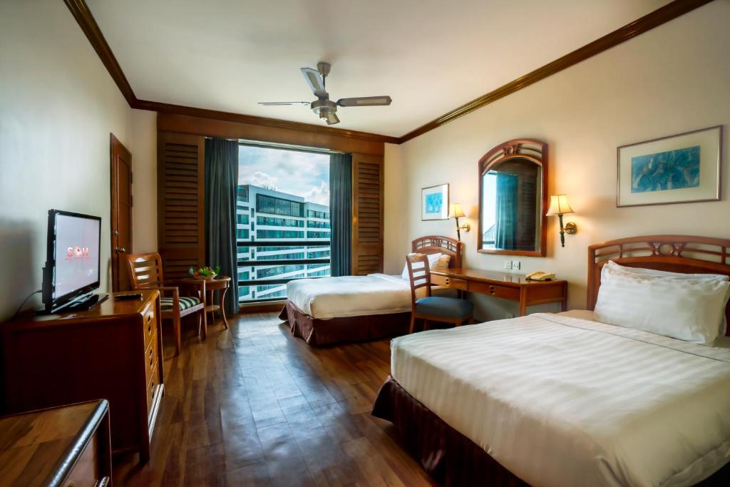 ein Hotelzimmer mit zwei Betten und einem Fenster in der Unterkunft Sabah Oriental Hotel in Kota Kinabalu