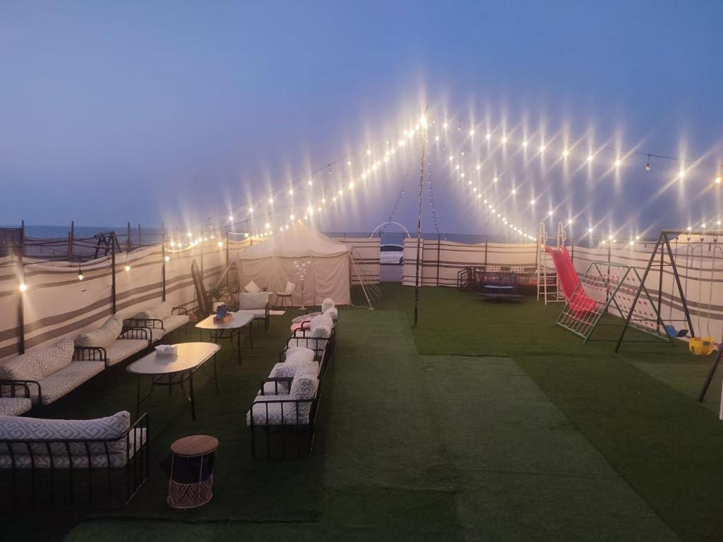 una carpa con mesas, sillas y luces en Laqa comp Oman - مخيم لقى عُمان, 